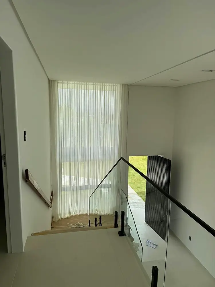 Escada com Vertflex em linho diante da janela alta.