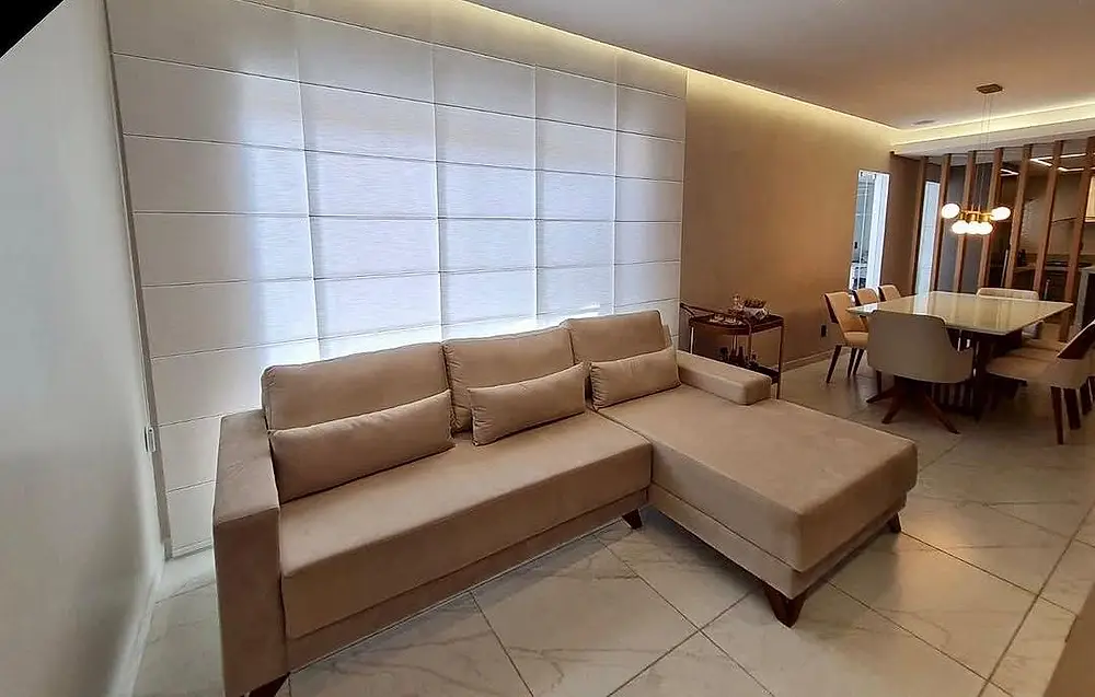 Sala integrada com cortina clara e chaise bege