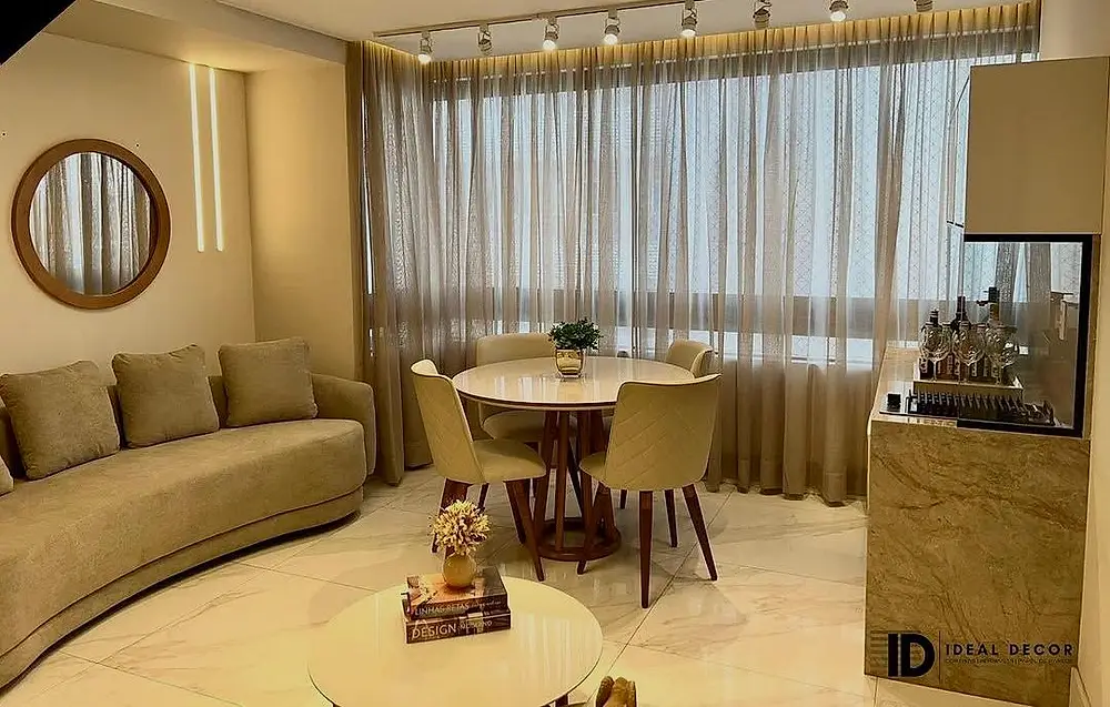 Sala de jantar com mesa redonda e cortina clara cobrindo a parede de vidro