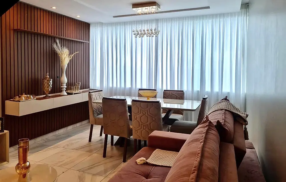 Sala de jantar com cortina em microfibra e painel ripado de madeira