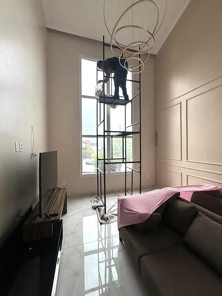 Instalador ajustando a cortina em uma janela alta, usando andaime.